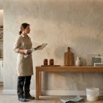 Female interior finisher admiring completed textured decorative plaster feature wall.
