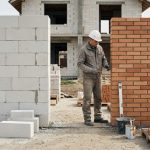 Будівельник порівнює стіни з газоблоку та цегли на будівництві